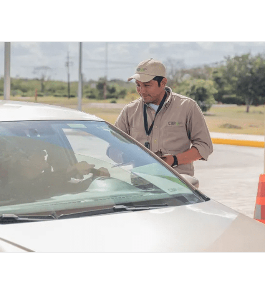 Controllo di sicurezza all’ingresso con personale che interagisce con una persona in auto